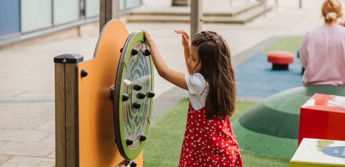 Child playing with educational outdoor playground equipment.